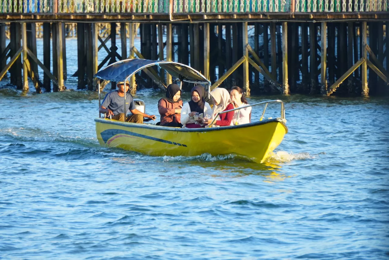 Para wisatawan lokal yang sedang menikmati perjalanan wisata menggunakan perahu.