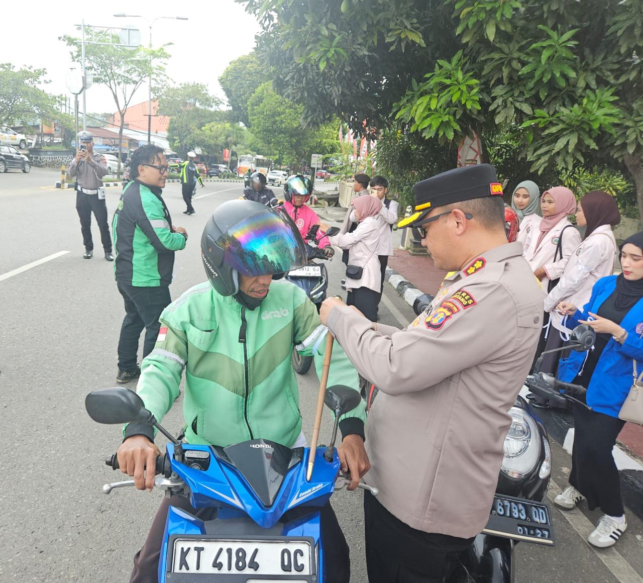 Kapolres Bontang AKBP Widho Anriano (kanan) saat membagikan pita ke pengemudi Ojol di depan Polres Bontang, Sabtu 30 Agustus 2025.