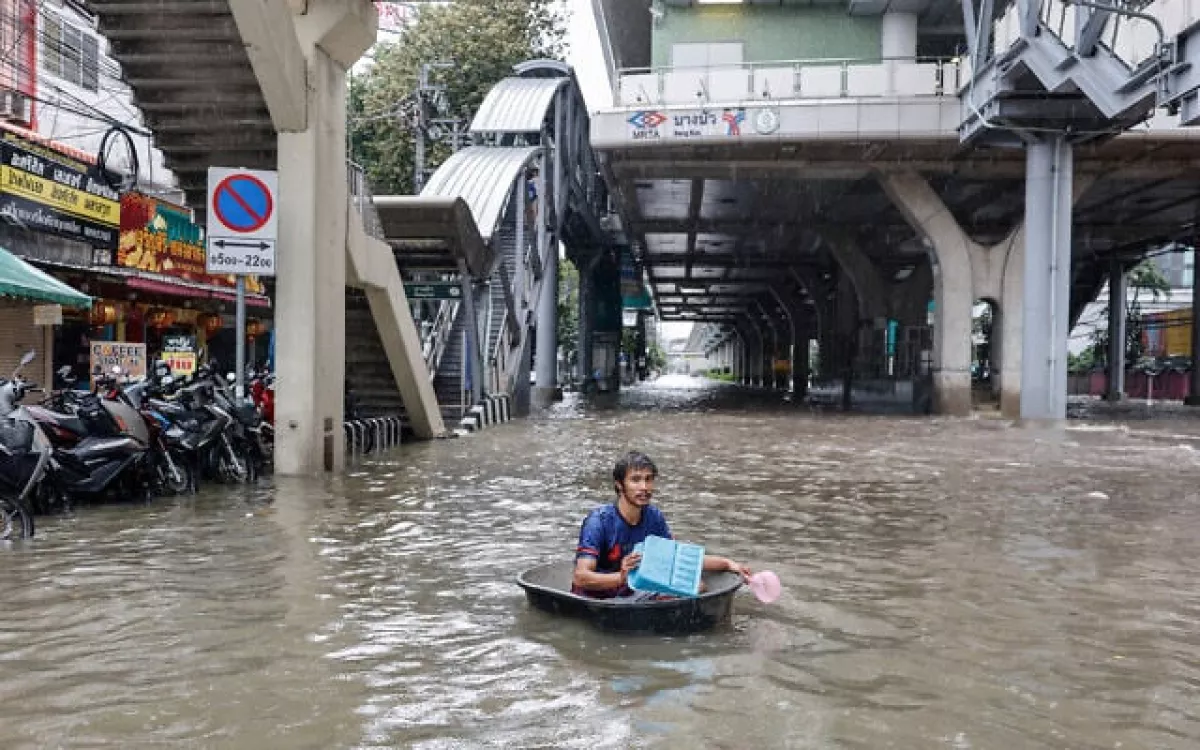 Seorang pria menggunakan tabung plastik besar untuk menerjang banjir di distrik Bang Bua, Bangkok. (AFP)